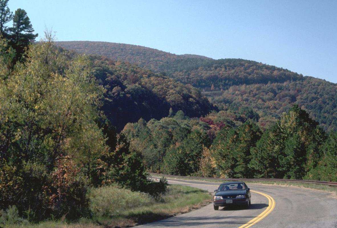 A lone vehicle winds its way around Winding Stair and Rich Mountains.