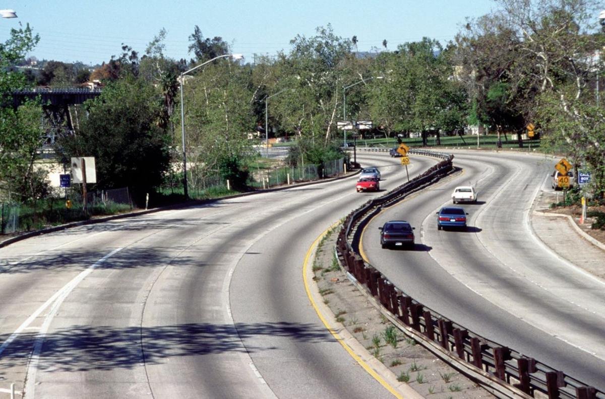 This typical view of parkway shows 6 lanes, curving alignment, native sycamore trees and LA-Pasadena historic railroad bridge in background.
