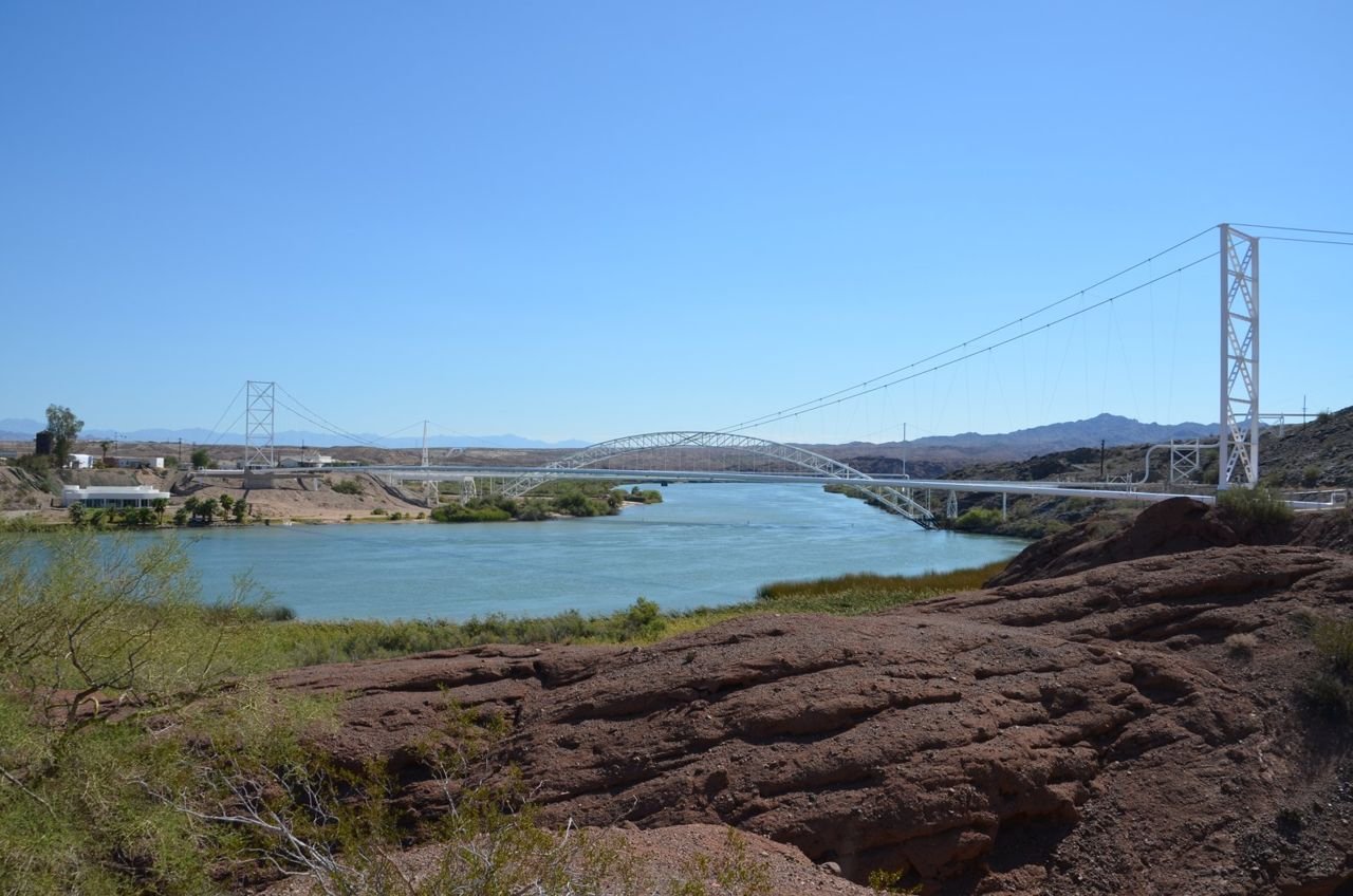 From a rocky knoll, the Colorado River gently flows downstream with the magnificent Trails Arch Bridge in the background. The River forms the natural boundary separating Arizona and California. Once on the
California side, Route 66 travelers could rest and prepare themselves for an incredible and dangerous journey. Looking forward a once-in-a-lifetime adventure on Route 66 across the desolate but beautiful Mojave Desert.
Looking back, the graceful, refreshing waters of the Colorado River.