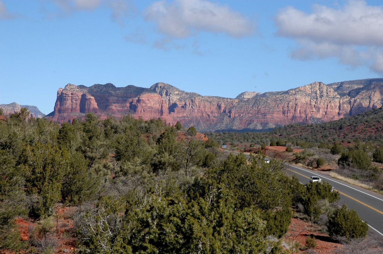 Scrub brush lines the roadway of the Red Rocks Scenic Byway.