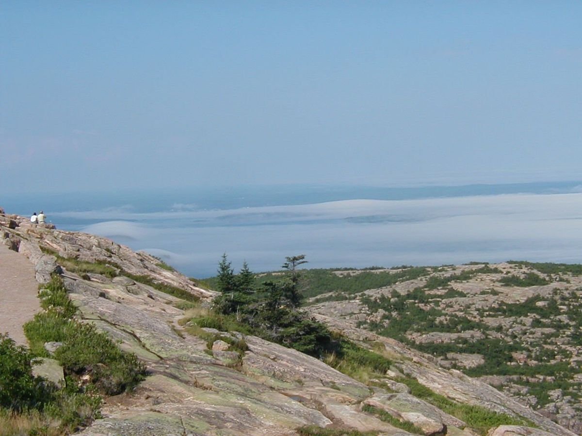 Summer fog blankets the distant landscape below a clear sky in this view from Cadillac Mountain.