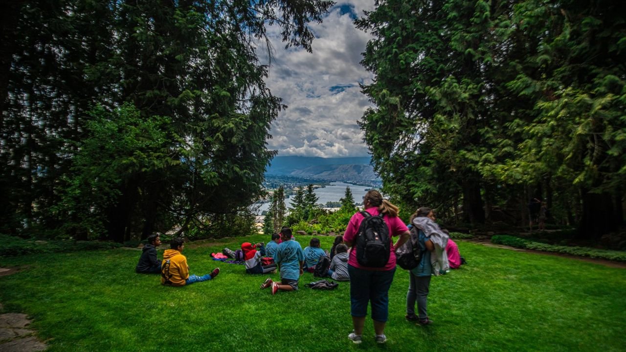 A group gathers in the grass at Ohme Gardens overlooking the Wenatchee Valley